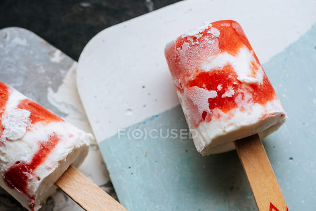 Closeup of two watermelon and cream popsicles on boards on dark background — Stock Photo