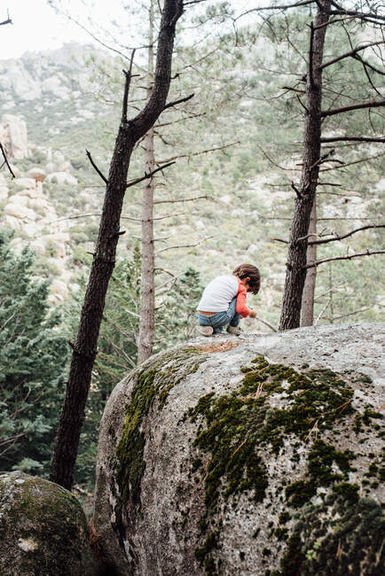 Little curious kid walking down rocky hillside exploring nature — Stock Photo