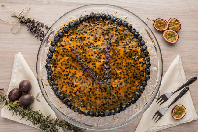 Appetizing fragrant passion fruit pie with blueberry topping decorated with bunch of lavender on cake stand — Stock Photo