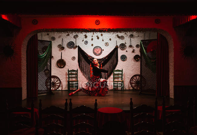 Танцовщица в костюме фламенко, стоящая в танцевальной позе в этнической комнате с антикварными предметами на стене — стоковое фото