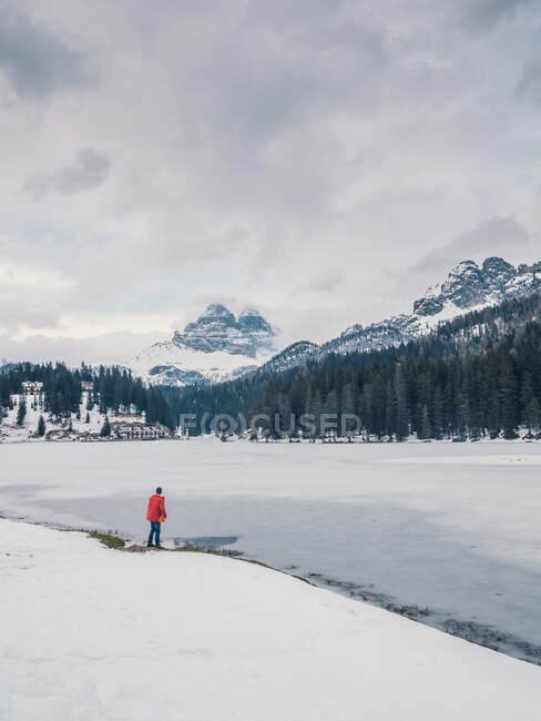 Неузнаваемый человек, стоящий в снегу в окружении леса и гор — стоковое фото