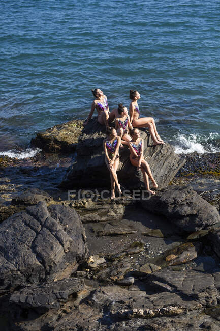 Grupo de gimnastas rítmicos relajándose sobre rocas - foto de stock