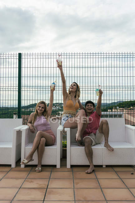 Группа друзей во время вечеринки у бассейна, танцуют, смеются и пьют коктейли — стоковое фото