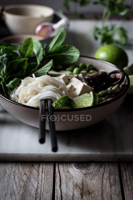 Served Pho soup with noodles on marble board on wooden table — Stock Photo
