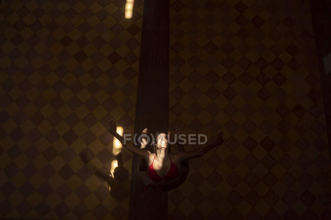 From above female dancing with raising hands under sunbeams in dark church in Morocco — Stock Photo