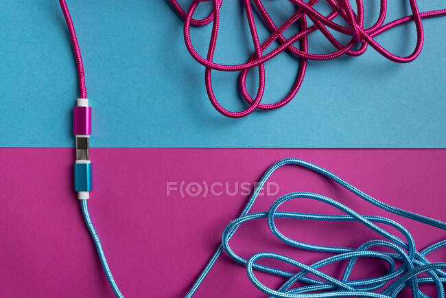 Vista dall'alto dei cavi USB colorati rosa fluo e blu su sfondo di cartone colorato — Foto stock