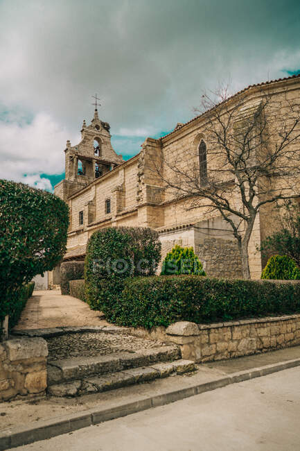 Зовнішній вигляд красивої старої церкви з кам'яною стіною і старі кроки в зеленому саду — стокове фото