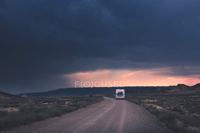 Rimorchio in piedi sul lato della strada vuota sotto drammatico cielo tempestoso — Foto stock