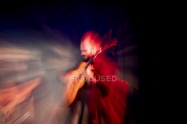 Homem hispânico tocando guitarra acústica durante a performance do flamenco no palco escuro — Fotografia de Stock