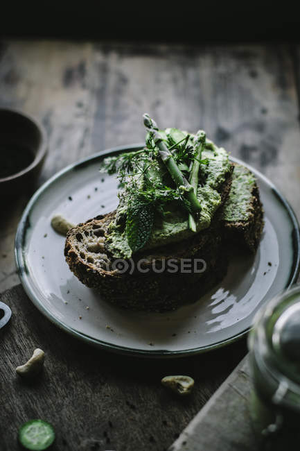 Toasts à la noix de cajou vert pâté, herbes et tranches de concombre sur assiette — Photo de stock