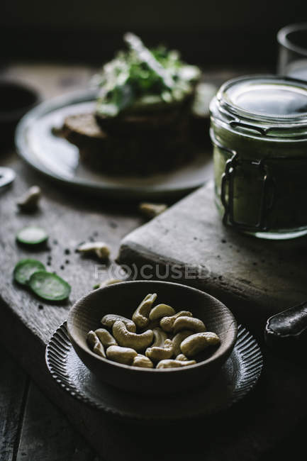 Piccola ciotola di legno di anacardi crudi per la preparazione di patè vegan verde su tavola di legno — Foto stock