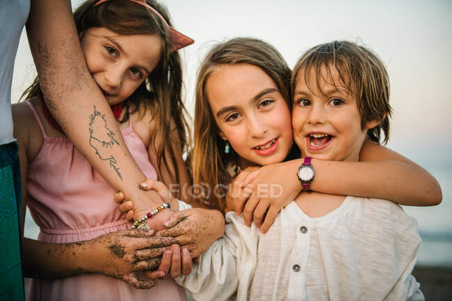 Crop view of anonymous woman with adorable daughters and son embracing on beach — Stock Photo