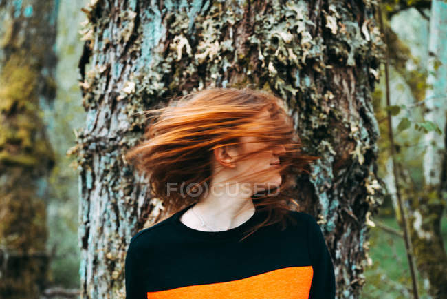 Bella giovane donna in felpa casual agitando con i capelli color zenzero contro il vecchio albero, Scozia — Foto stock