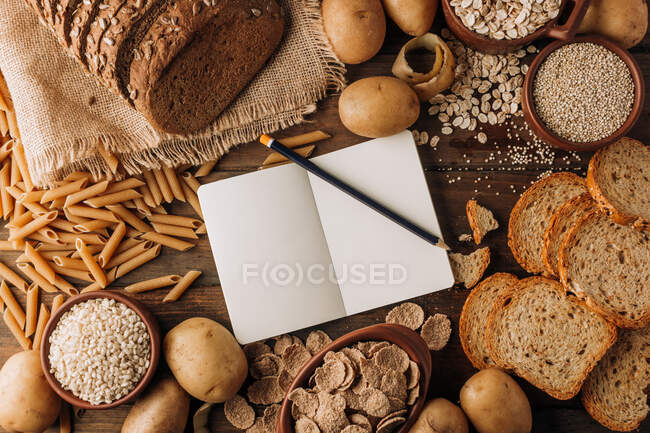Wholegrain food empty notebook and freshly baked rye bread on table — Stock Photo
