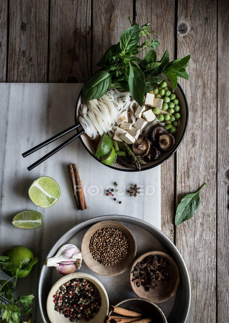 Served Pho soup with noodles on marble board on wooden table with spices — Stock Photo