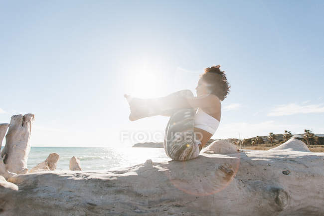 African American woman in yoga posture on background of calm water in sunny day — Stock Photo