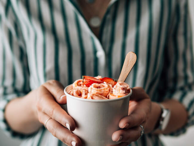 Crème glacée roulée à la fraise dans une tasse à cône dans les mains de la femme. Tasse à cône à main avec glace roulée style thaï — Photo de stock