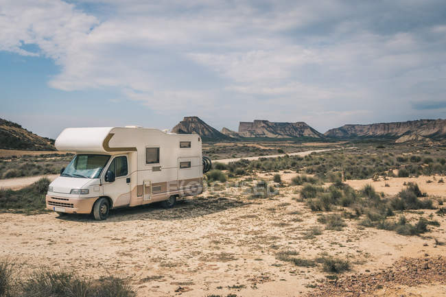 Білий трейлер, припаркований в пустелі з горами на фоні — стокове фото