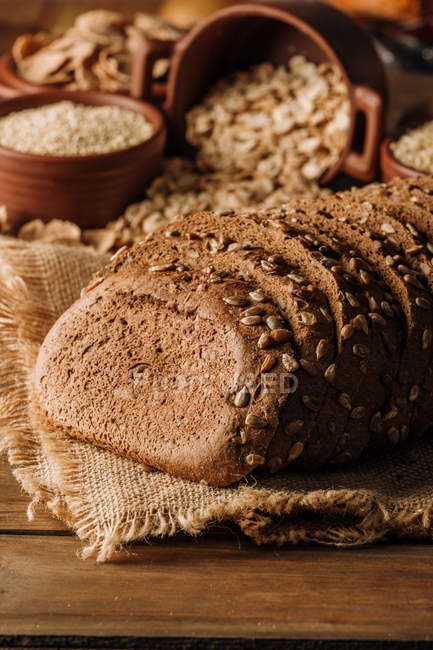 Pan de centeno recién horneado en rodajas en servilleta sobre mesa de madera - foto de stock