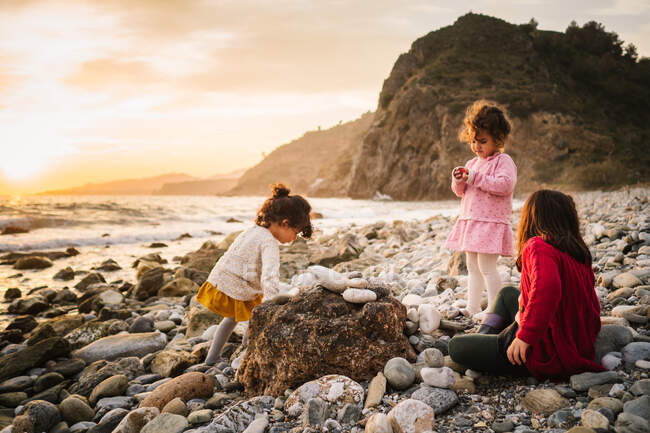 Близнецы играют на каменистом побережье на фоне спокойной воды — стоковое фото