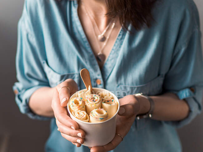 Rolled ice cream in cone cup in woman hands. Woman in jeans shirt holds cone cup with thai style vanilla rolled ice cream — Stock Photo