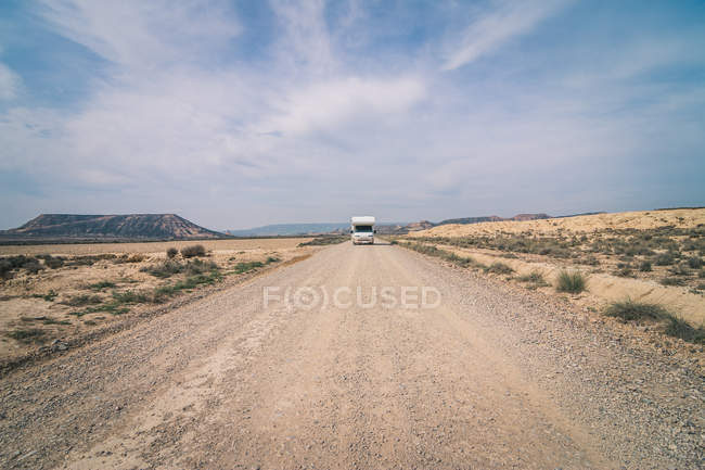 Білий трейлер їде порожньою дорогою вздовж пустелі — стокове фото