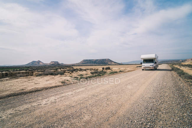 Білий трейлер їде порожньою дорогою вздовж пустелі — стокове фото