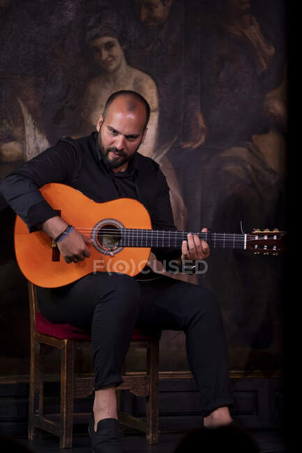 Bald barbudo cara tocando guitarra acústica enquanto sentado no palco durante a performance de flamenco — Fotografia de Stock