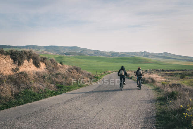 Men riding bicycles on road in desert hills — Stock Photo