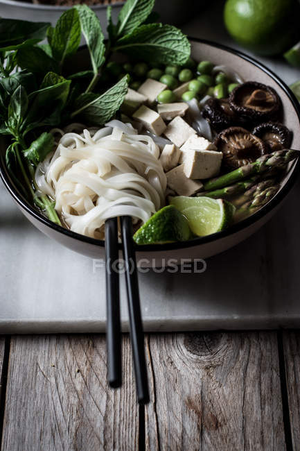 Soupe Pho servie avec nouilles sur panneau de marbre sur table en bois — Photo de stock