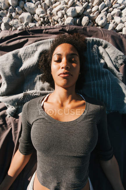 Retrato de afro-americano atraente jovem deitado na praia de seixos — Fotografia de Stock