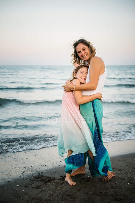 Smiling adult woman with charming girl embracing and looking at camera — Stock Photo