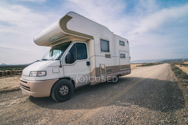 Camper bianco parcheggiato su strada vuota lungo semi-deserto con vegetazione secca — Foto stock