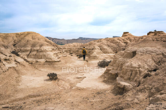 Homem caminhando na paisagem incrível de colinas do deserto no fundo do céu azul — Fotografia de Stock