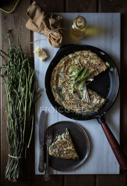 From above of skillet pan with fried tortilla with fresh asparagus and onion served on board with ingredients — Stock Photo