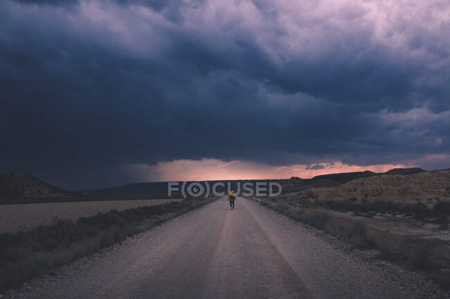 Homme debout sur la route et regardant le ciel impressionnant du soir — Photo de stock