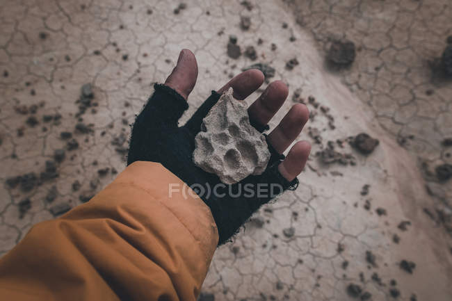 Closeup of stone in hand on dry desert area — Stock Photo
