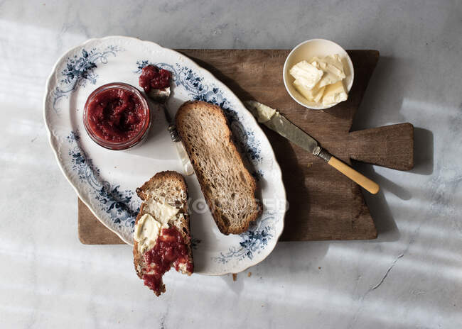 Vista dall'alto del piatto con croissant croccante e burro e marmellata di fragole servita su tavola di legno — Foto stock