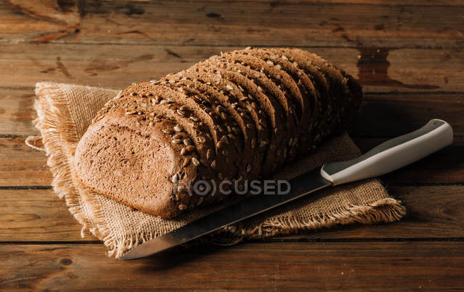 Свіжоспечений нарізаний житній хліб на серветці на дерев'яний стіл — стокове фото
