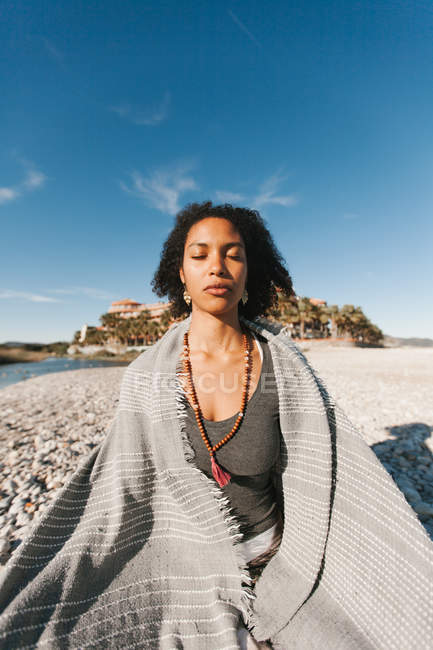 Afro-américaine jeune femme méditant dans la posture de yoga lotus sur la plage de sable fin dans la journée lumineuse — Photo de stock