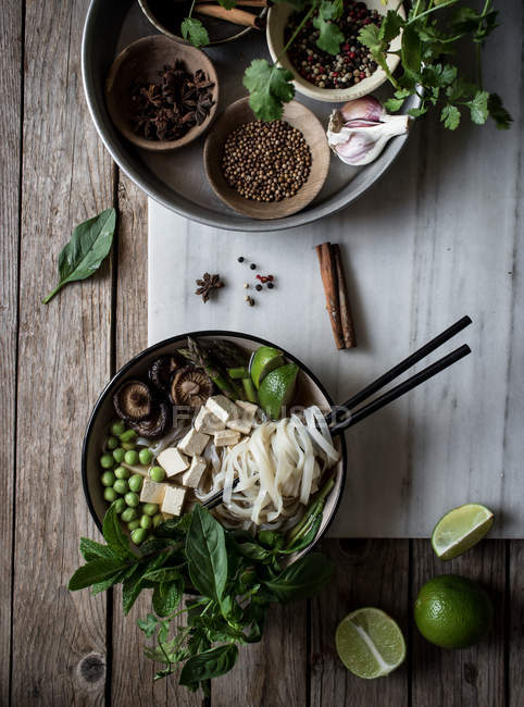Serviert Pho-Suppe mit Nudeln auf Marmorplatte auf Holztisch mit Gewürzen — Stockfoto