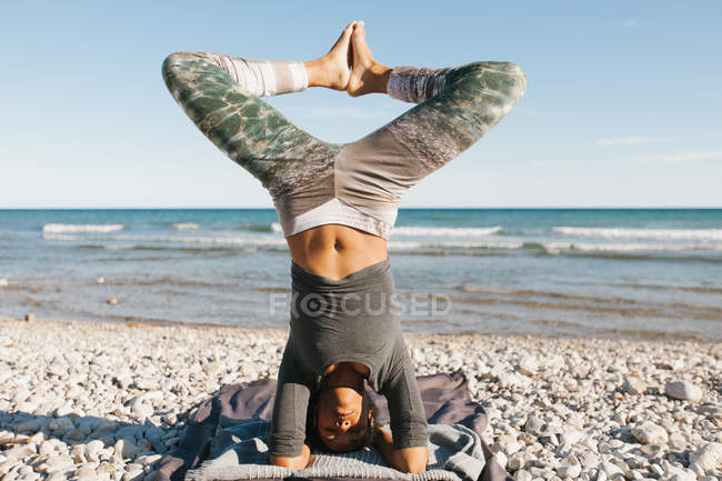 Jovem afro-americana em postura de cabeça de ioga no fundo do mar calmo no dia ensolarado — Fotografia de Stock