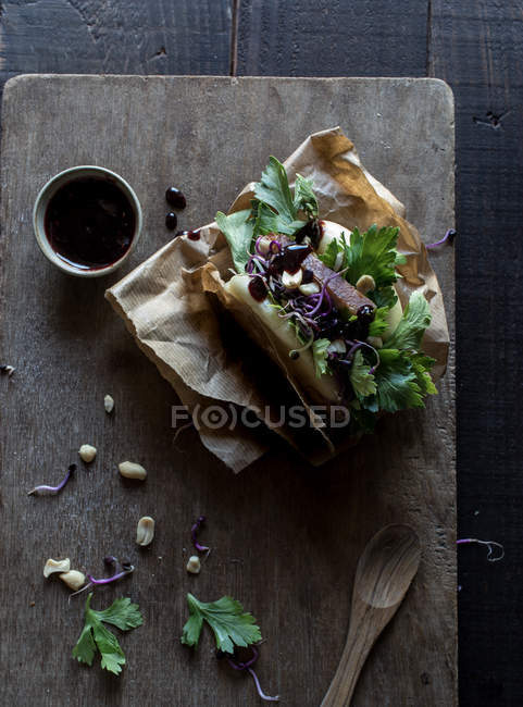 From above of delicious traditional Gua Bao sandwich with parsley and grain sprouts served on board with sauce — Stock Photo