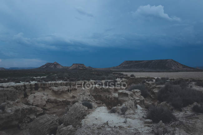 L'uomo in piedi sulla pietra nelle colline desertiche — Foto stock