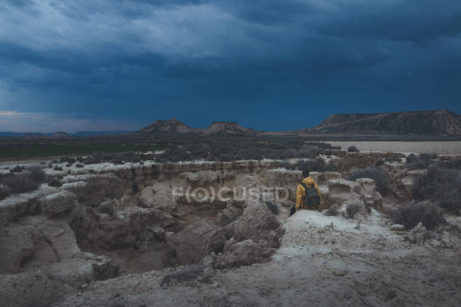 Человек, стоящий на камне в пустынных холмах — стоковое фото