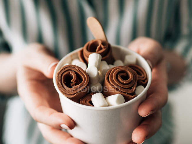 Gelato al cioccolato arrotolato in tazza di cono nelle mani della donna. Tazza cono mano con gelato al cioccolato in stile tailandese — Foto stock