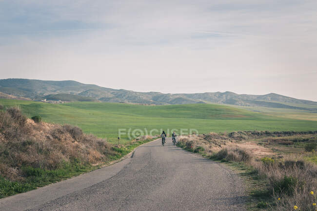 Männer mit Fahrrädern auf Straße in wüsten Hügeln — Stockfoto