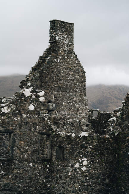 Aged medieval stone building with mountains behind it covered in fog, Scotland — Stock Photo