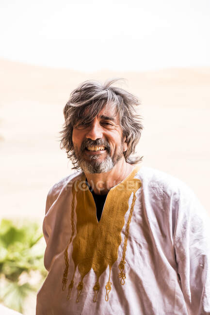 Портрет дорослої людини в довгому спорядженні з пустелею на задньому плані і фотоапарат, Марокко. — стокове фото