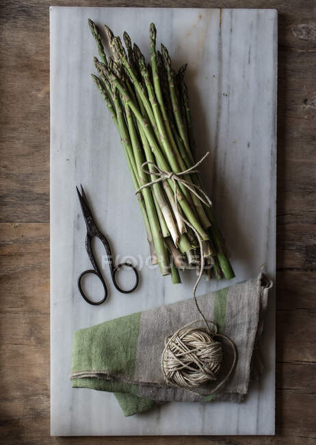 Vista dall'alto della tavola di marmo con mucchio di asparagi legati con corda ritorta sul tavolo di legno — Foto stock